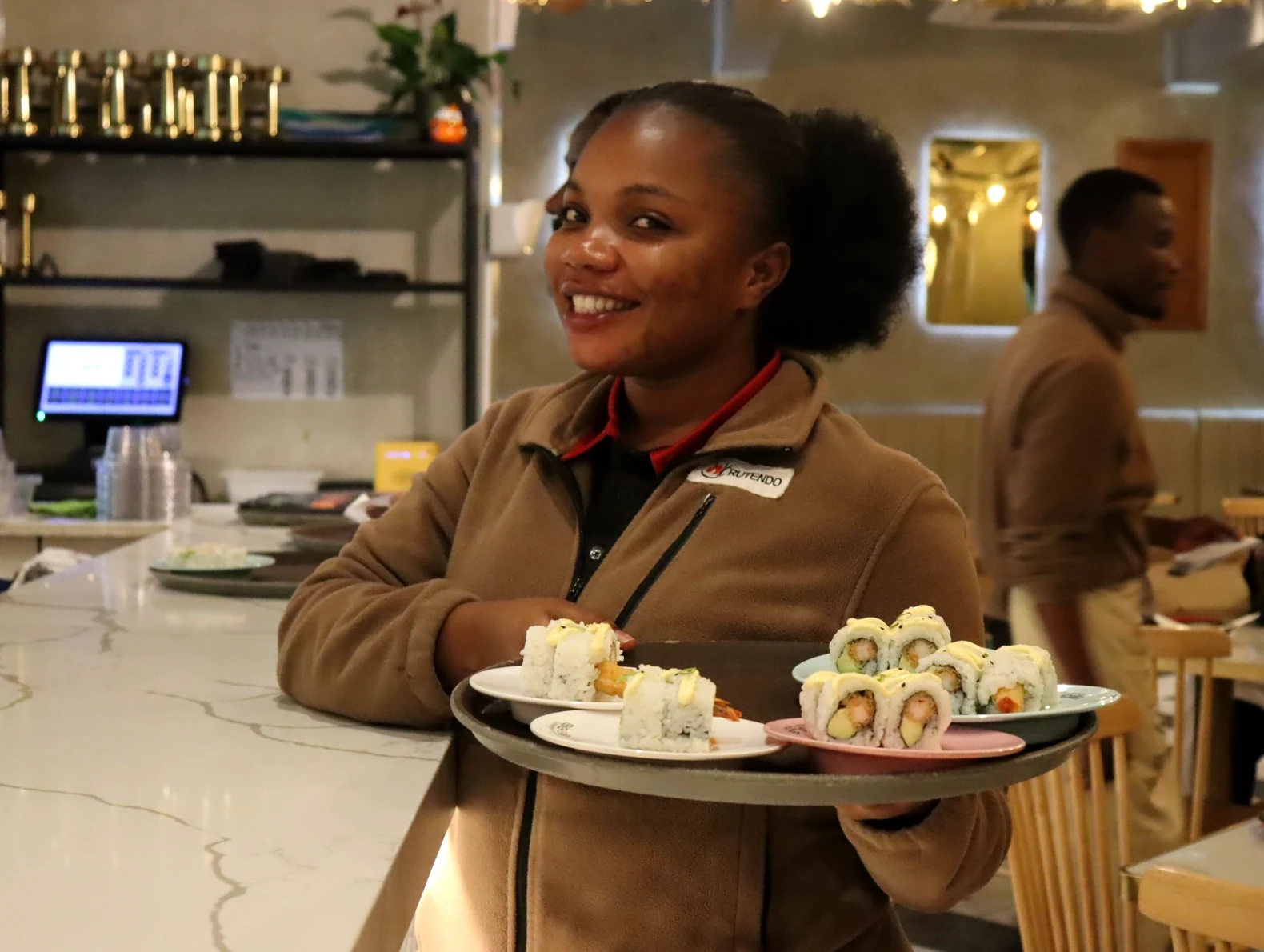Smiling Big Bowls team member presenting freshly prepared sushi